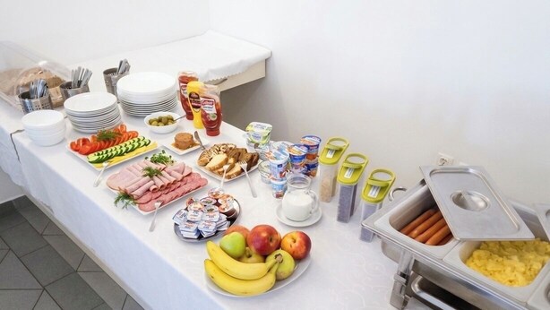 A buffet table with various food items, utensils, and condiments.