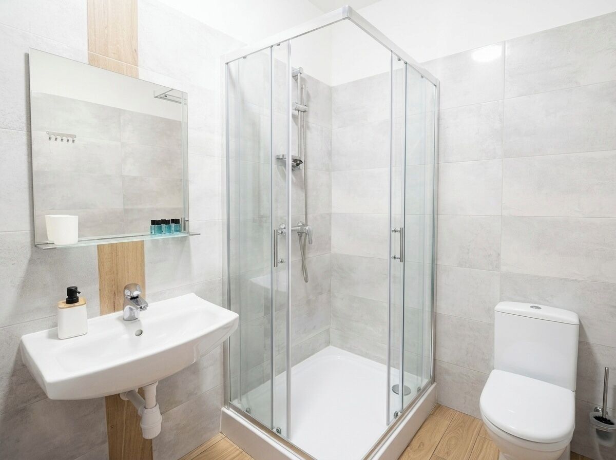 A modern bathroom with a glass-enclosed shower, a white sink, and a toilet.