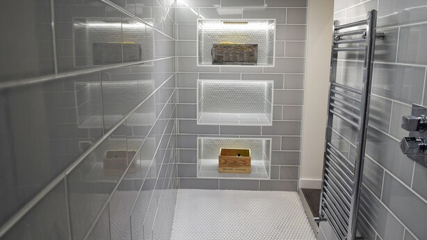 A modern bathroom with grey tiled walls, a glass shower enclosure, and a built-in towel rack. - Toothbrush Apartments - Central Ipswich - Fore St - Adults Only (Ipswich)