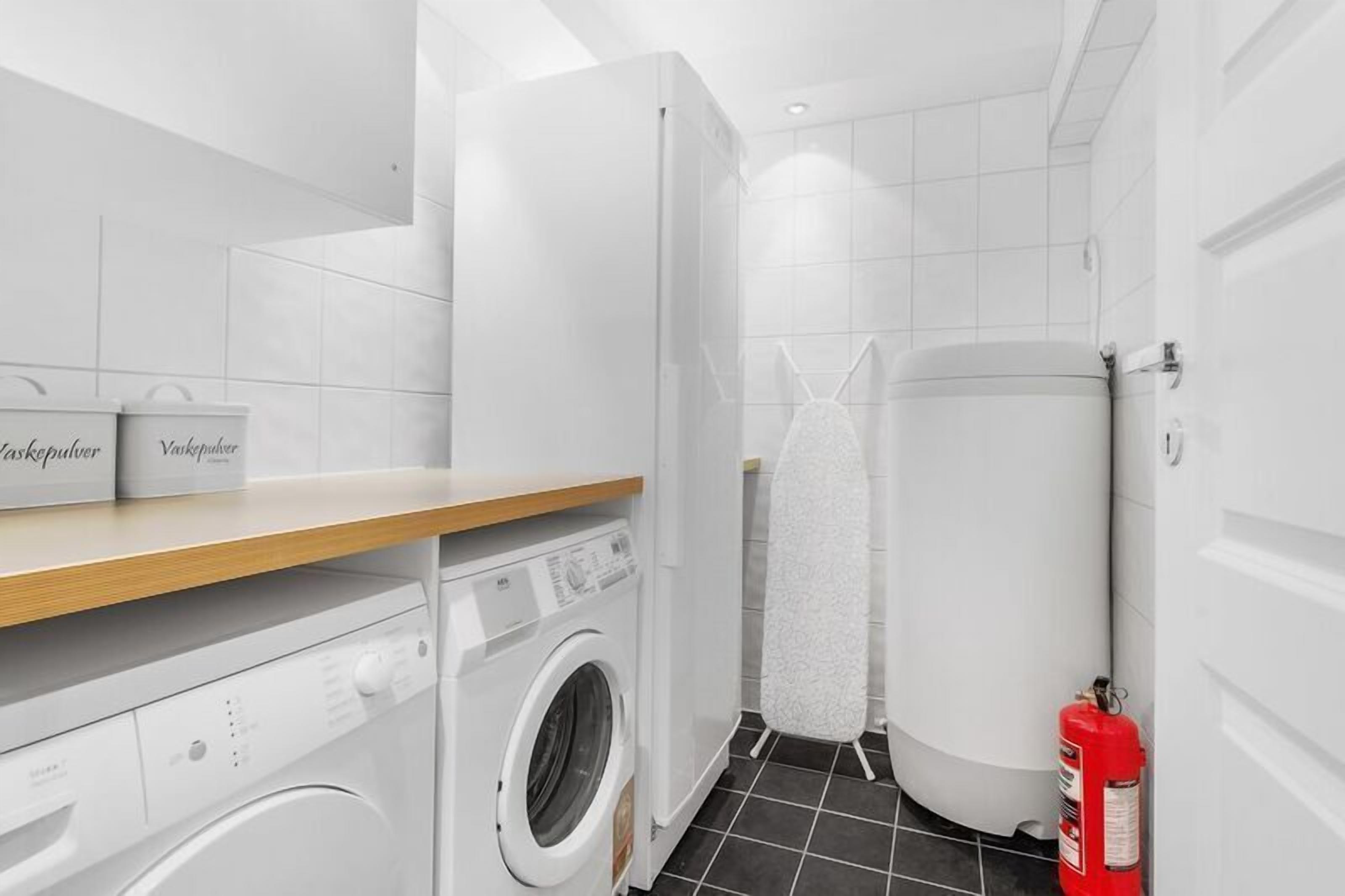 Een kleine wasruimte met een wasmachine, een droger en een brandblusser.