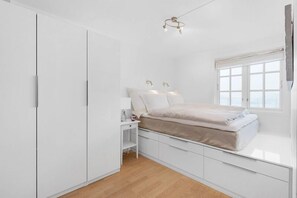 Une chambre à coucher avec un lit, des tables de chevet, une armoire et une fenêtre donnant sur un beau paysage.