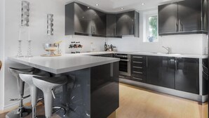 Une cuisine moderne dotée d’un îlot central, de tabourets de bar et de meubles de rangement noirs.
