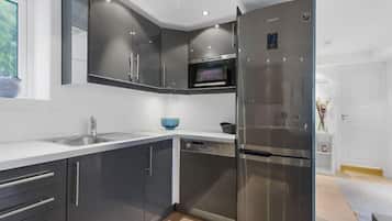 A modern kitchen with dark cabinets, stainless steel appliances, and a built-in oven.