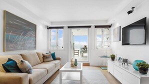 Un salon moderne avec un canapé beige, une table basse blanche et un grand tableau abstrait.