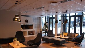 Moderni olohuone, jossa on takka, mukavat istuimet ja suuret ikkunat.