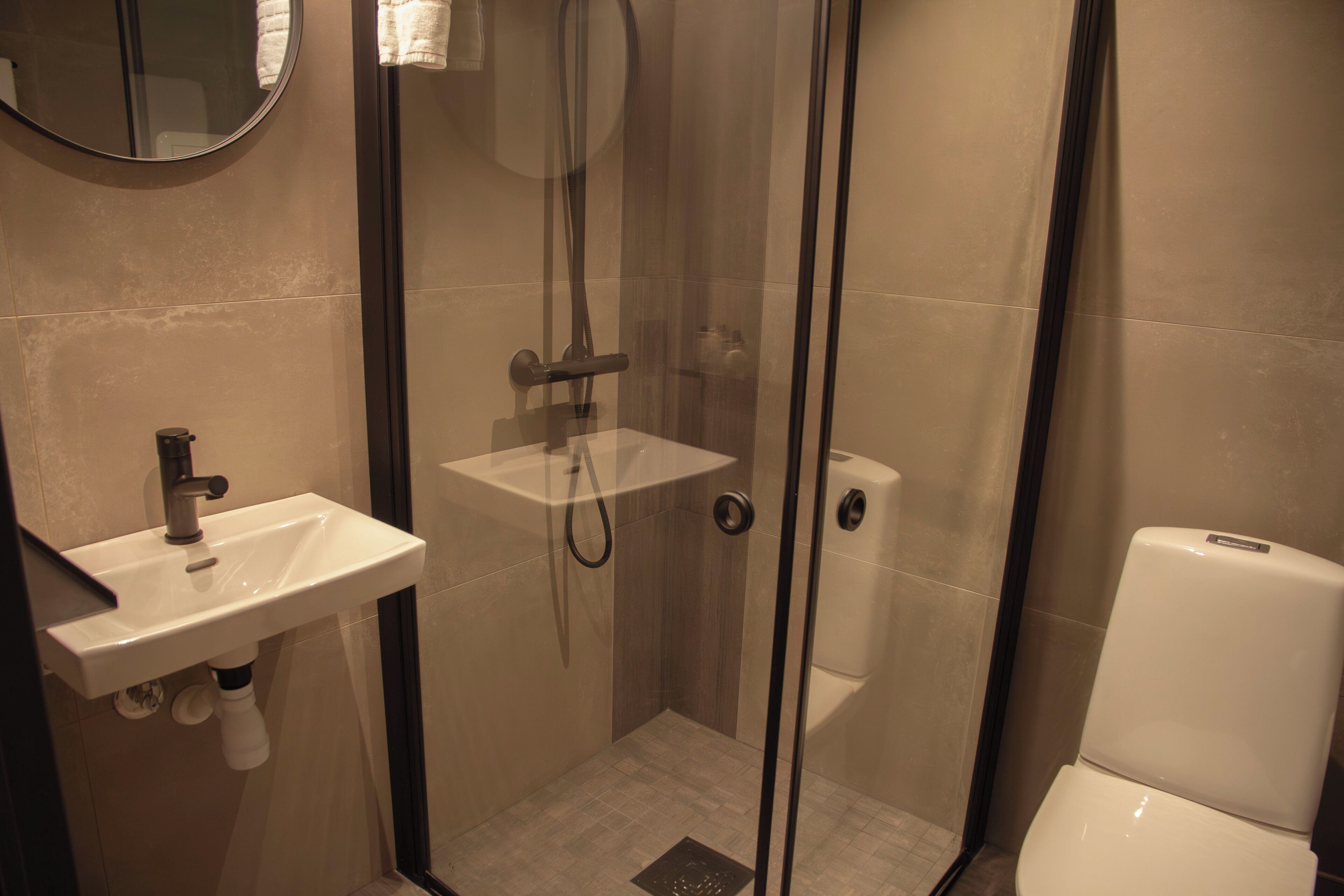 Un baño con cabina de ducha de vidrio, un lavamanos con espejo y un inodoro.