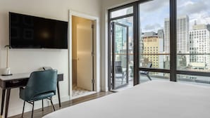 A hotel room with a bed, a desk with a chair, a TV, and a large window with a city view. - The Draper New York, Tapestry Collection by Hilton (New York)