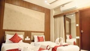 A hotel room with two beds, each with red and white bedding, a large mirror, and a wooden headboard. - Grand Oliver (Chennai)