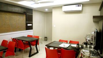 A dining area with red chairs, a table with a tray, and a ceiling fan.