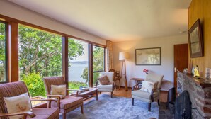 Un amplio salón con ventanas grandes, chimenea y asientos cómodos.