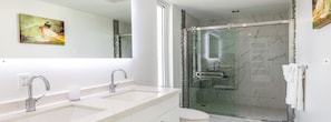Un baño moderno con dos lavamanos, cabina de ducha de vidrio y un inodoro.