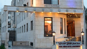 A hotel building with a sign reading "SAMA AMMAN HOTEL APARTMENTS".