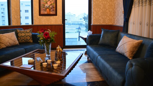 Ein modernes Wohnzimmer mit einem dunkelblauen Sofa, einem Glastisch und einer Blumenvase.