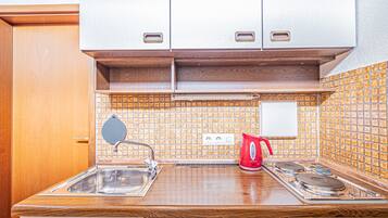 Una cocina pequeña con fregadero, estufa y armarios.