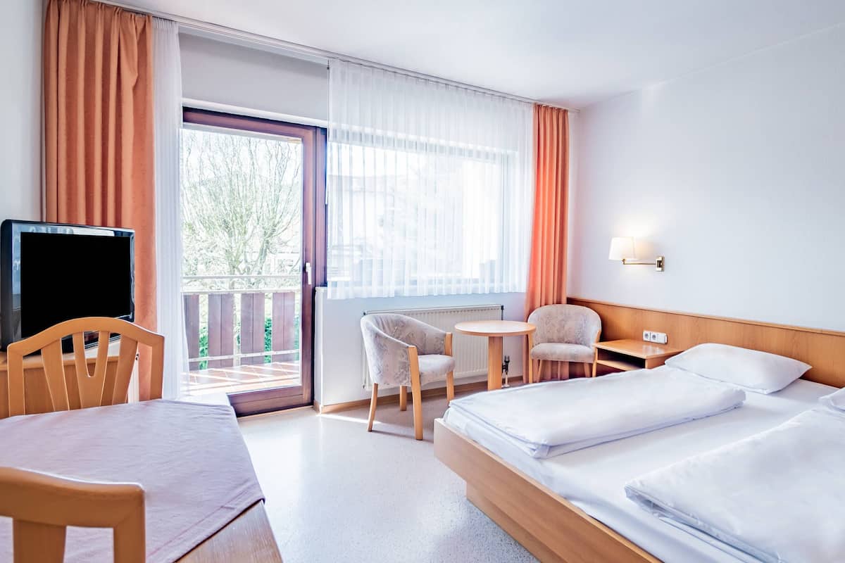 A hotel room with a bed, a desk, a chair, and a television.
