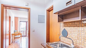 Una cocina con un lavamanos de acero inoxidable, armarios de madera y salpicadero de azulejos.
