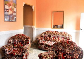 A room with four patterned armchairs, a white-framed mirror, and a framed picture on the wall. - Hostal San Miguel TRINIDAD (Trinidad)
