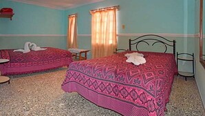 A room with two beds, each with a patterned bedspread and a white towel on one. - Hostal Tony y Daisy TRINIDAD (Trinidad)