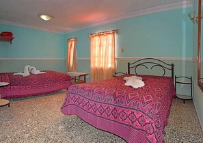 A room with two beds, each with a patterned bedspread and a white towel on one. - Hostal Tony y Daisy TRINIDAD (Trinidad)