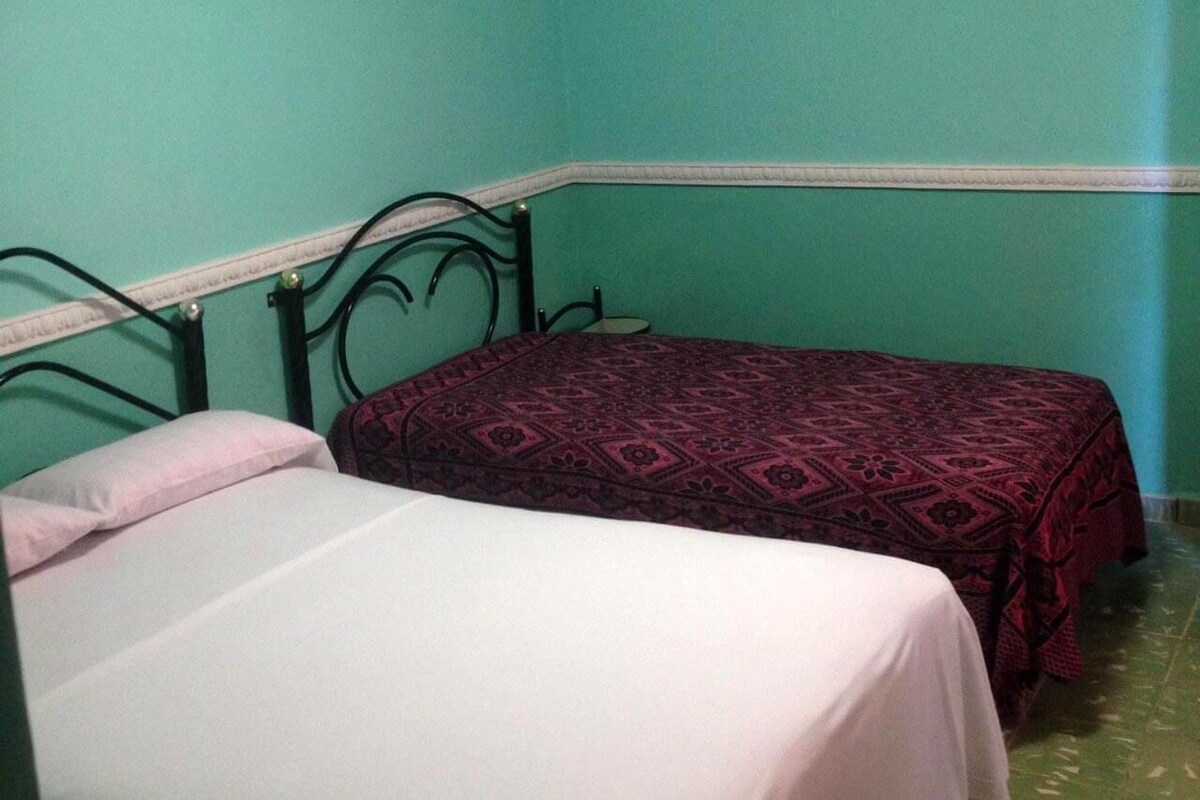 A room with two beds, one with a white bedspread and the other with a patterned bedspread.