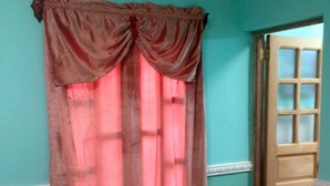 A room with a door and a window with a pink curtain. - Hostal Tony y Daisy TRINIDAD (Trinidad)