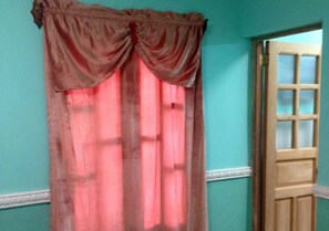 A room with a door and a window with a pink curtain. - Hostal Tony y Daisy TRINIDAD (Trinidad)