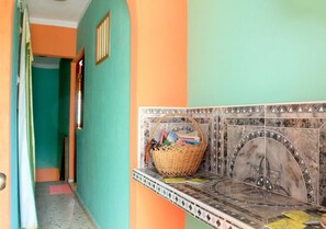 A hallway with a tiled wall, a basket on a shelf, and a door. - Hostal Yoeslin y Denis TRINIDAD (Trinidad)
