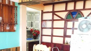 A room with a wooden ceiling, a fan, a window with a decorative frame, and a tiled backsplash. - La Moderna BARACOA (Baracoa)