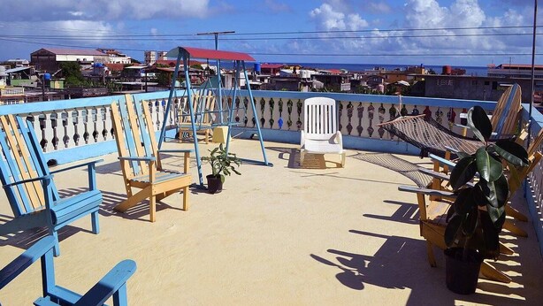 A beachside seating area with blue and wooden lounge chairs, a small table, and a potted plant. - La Moderna BARACOA (Baracoa)