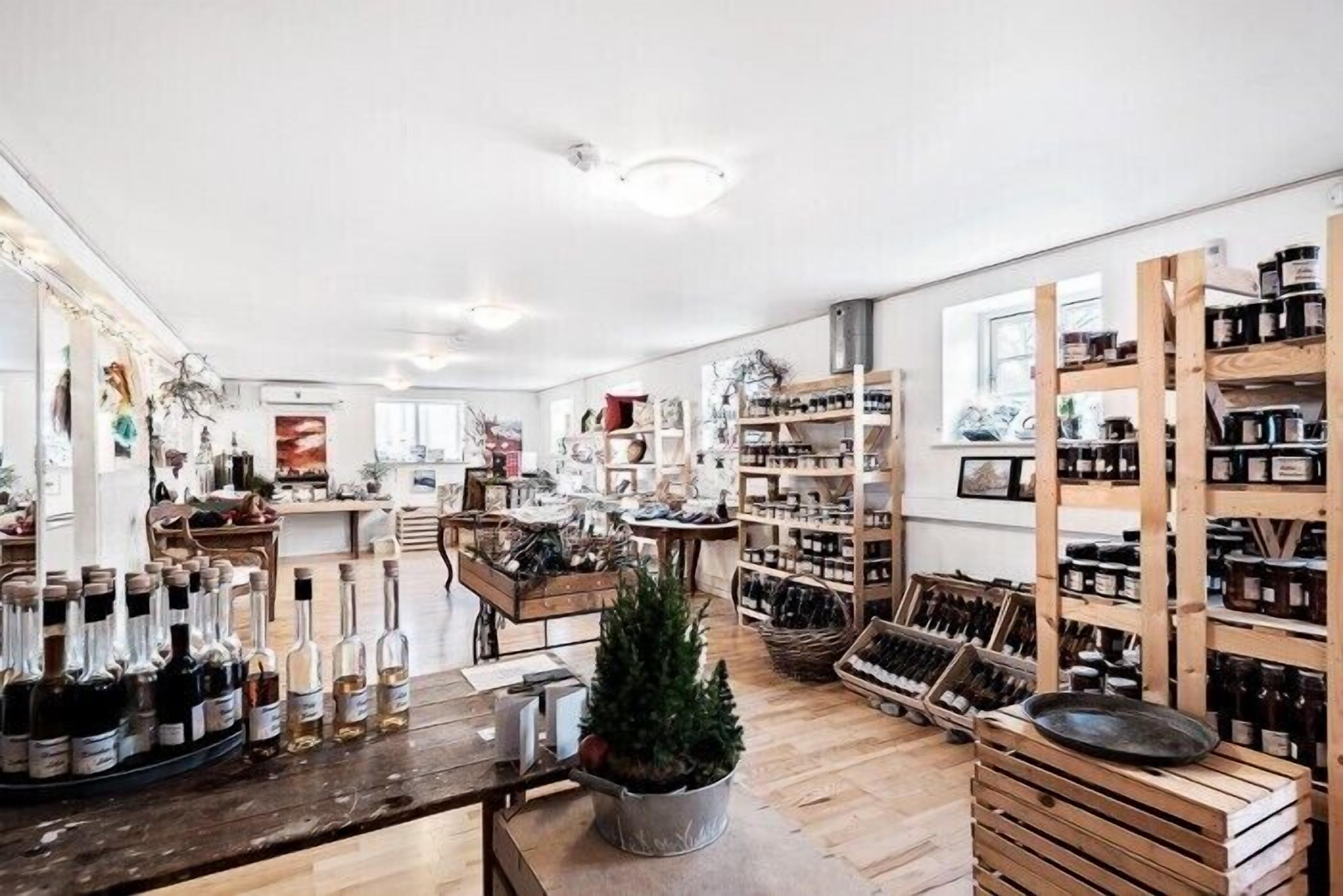 A spacious wine shop with wooden shelves and a central table displaying wine bottles.