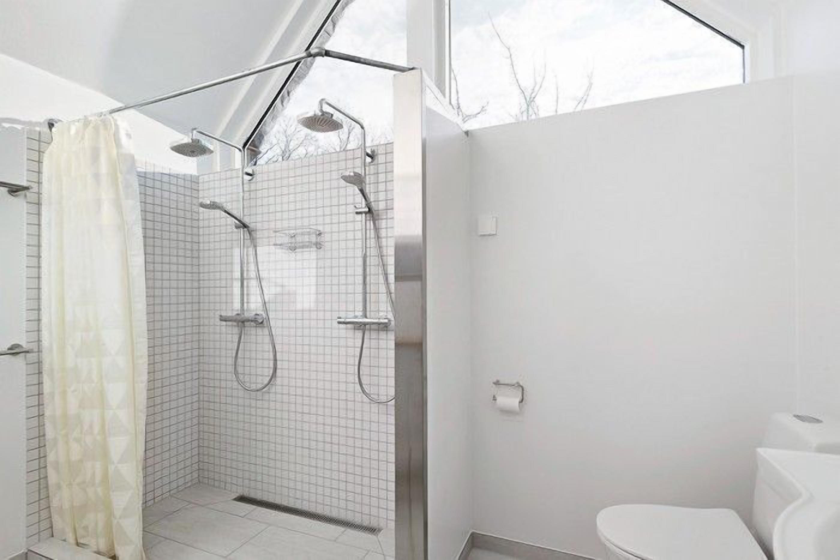A modern bathroom with a walk-in shower, a toilet, and a window providing natural light.