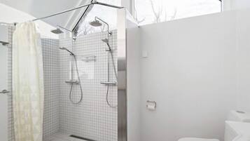 A modern bathroom with a walk-in shower, a toilet, and a window providing natural light.