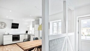 Una cocina moderna con armarios blancos, una mesa de comedor de madera y un ventanal grande.