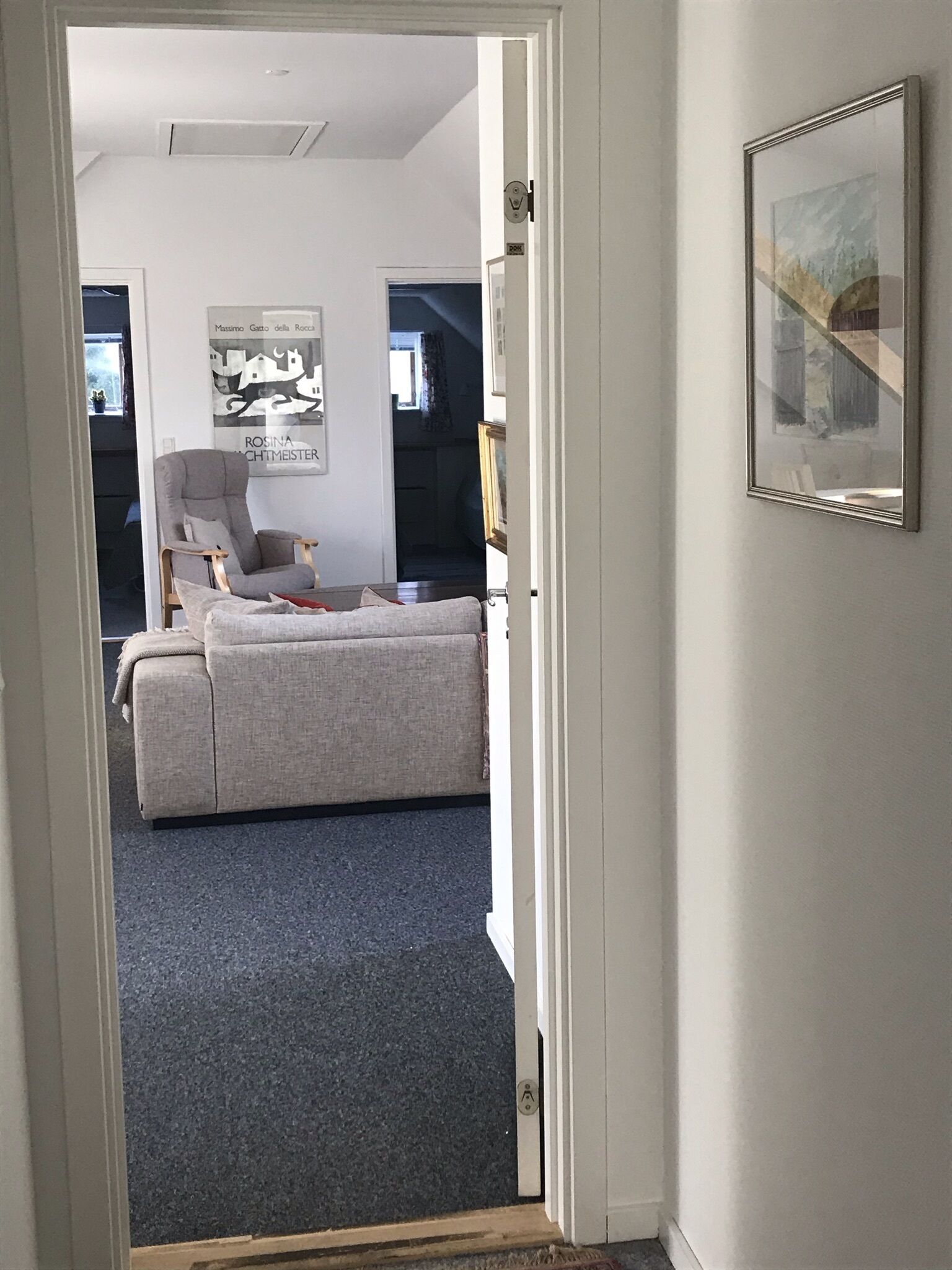 Una habitación con un sofá gris, una silla y un cuadro en la pared.