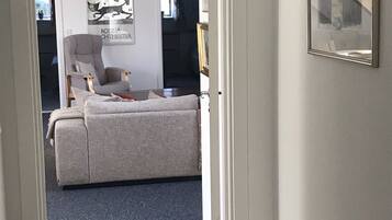 Una habitación con un sofá gris, una silla y un cuadro en la pared.