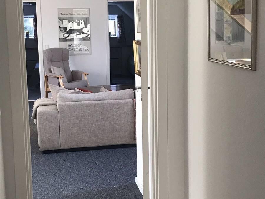 A room with a grey sofa, a chair, and a framed picture on the wall.