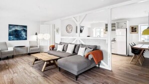 Una sala de estar moderna con un sofá seccional gris, una mesa de centro de madera y un comedor con una mesa y sillas de madera.