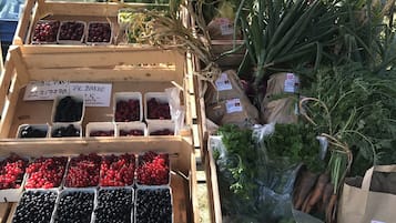 A wooden crate with various fruits and vegetables, including cherries and blackberries, displayed outdoors.