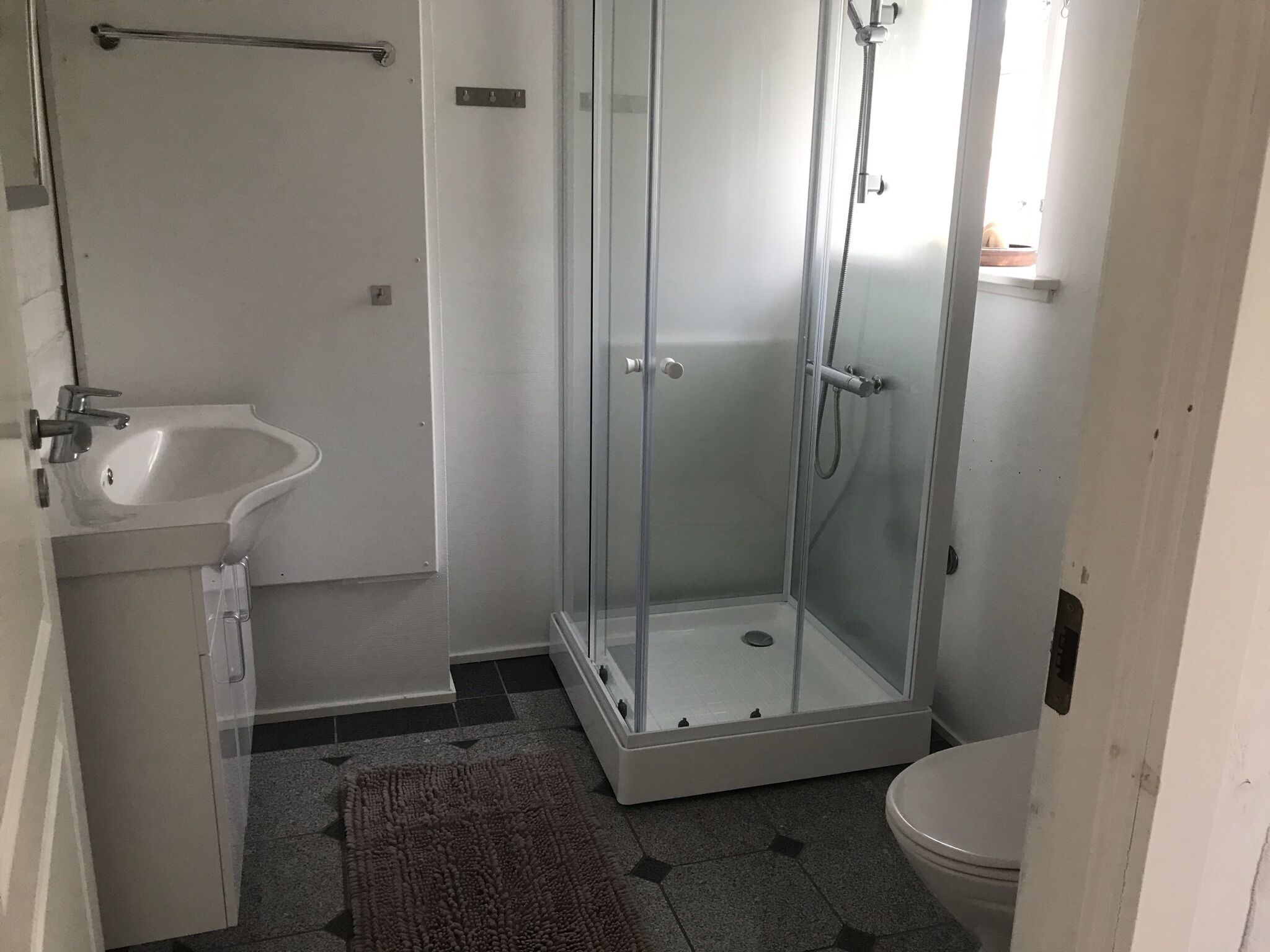Un baño pequeño con ducha envuelta en vidrio, lavabo e inodoro.
