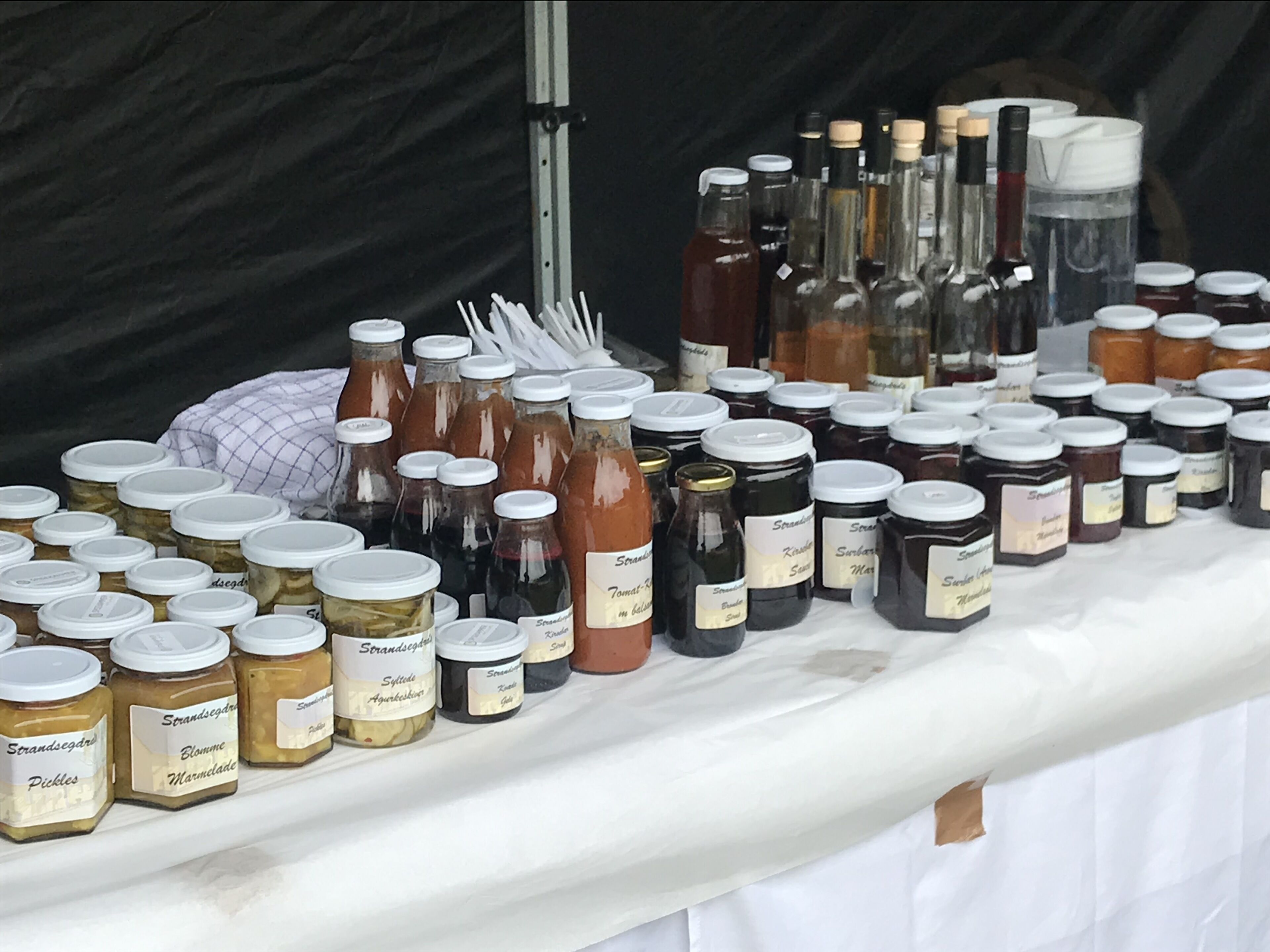 Une variété de pots et de bouteilles, probablement remplis de conserves ou de condiments, sont disposés sur une table.
