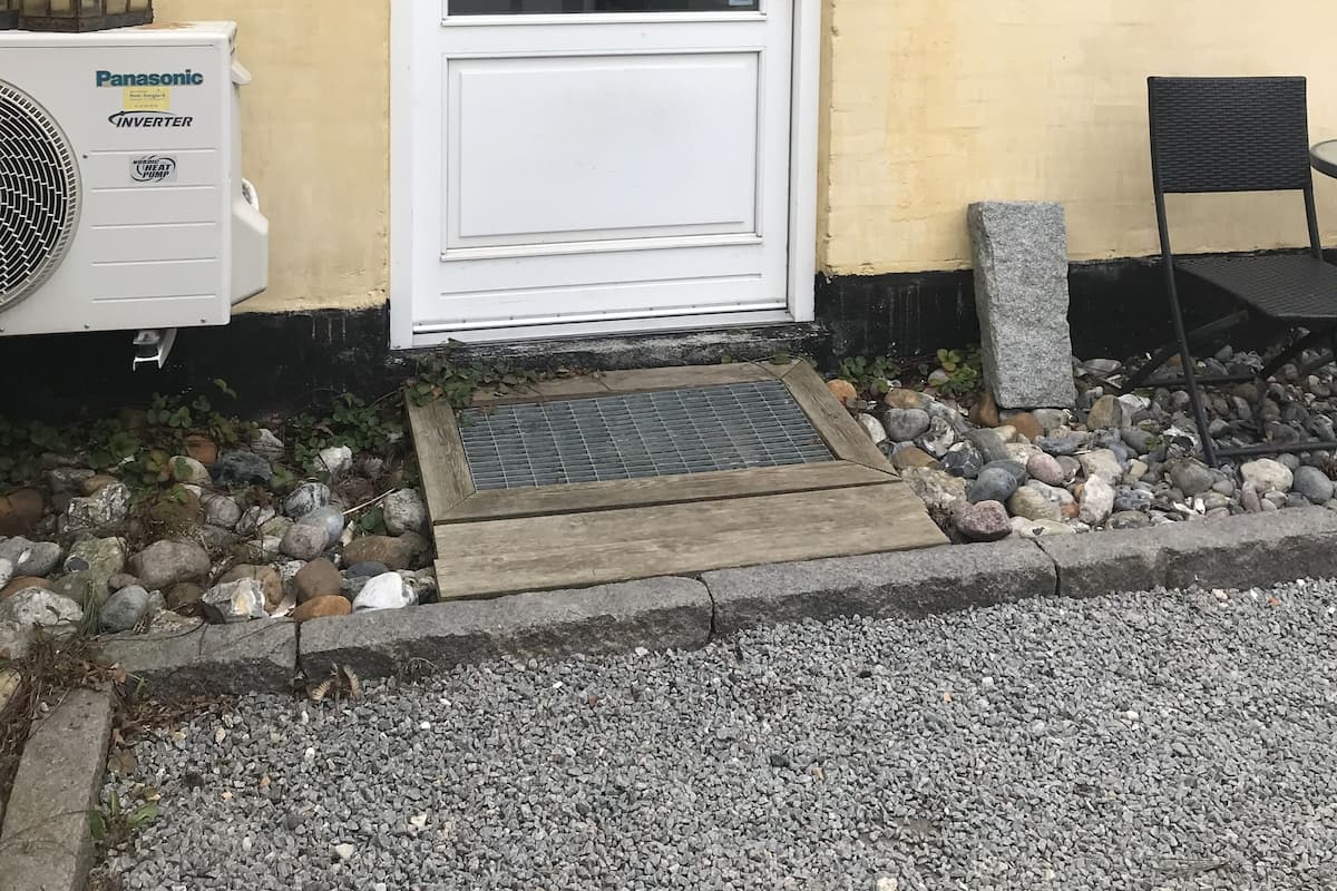 A building with a white door, a number '12' on the wall, and a Panasonic inverter unit outside.