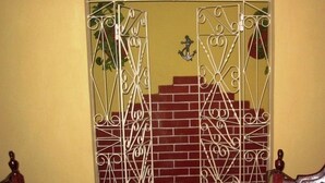 Una reja de hierro forjado con un diseño decorativo, un muro de ladrillo y un pequeño adorno con forma de ancla.