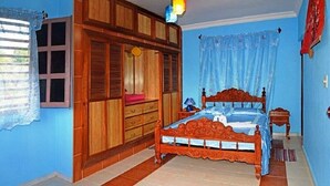 Un dormitorio con cama de madera, un armario y una lámpara en el techo.