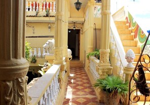A corridor with ornate columns, a tiled floor, and a staircase with colorful railings. - Hostal Ricardo Leon TRINIDAD (Trinidad)