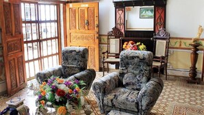Een klassieke kamer met gestreept fauteuils, een houten deur met gedetailleerde decoraties en een betegelde vloer.