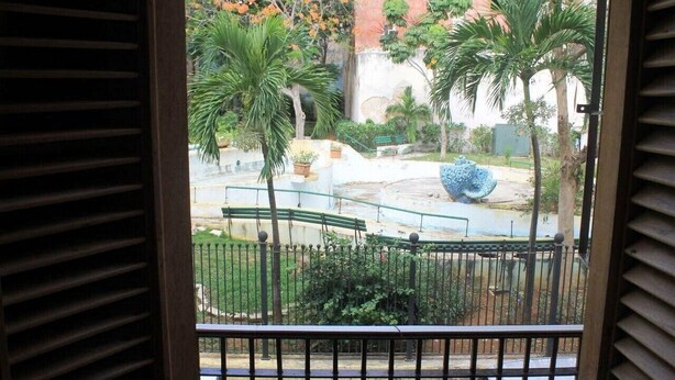 A balcony with a view of a park, including palm trees and a fountain. - Hostal Yolanda HABANA VIEJA (Havana)