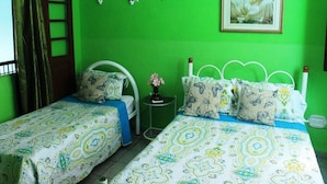 A room with two beds, green walls, a small table with a vase, and a framed picture on the wall. - Hostal Yolanda HABANA VIEJA (Havana)