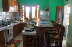 A kitchen with wooden cabinets, a stove, and a dining area with chairs and a table. - Sophi's House VEDADO (Havana)