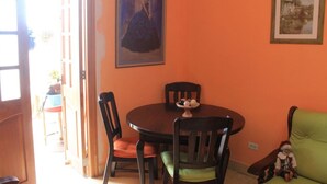 Een eetruimte met een ronde tafel, vier stoelen en een schilderij aan de muur.