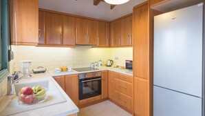 A kitchen with wooden cabinets, a stainless steel refrigerator, a built-in oven, and a coffee maker.